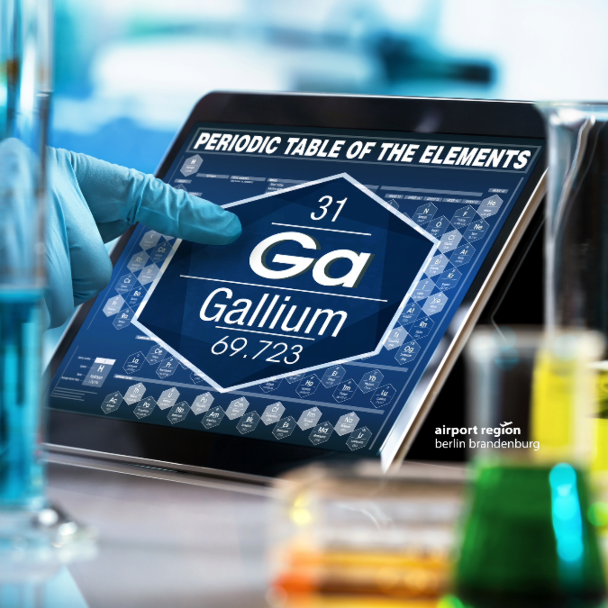 Bild zeigt eine menschliche Hand in einer Laborumgebung die auf ein Display zeigt. Das Display zeigt einen Ausschnitt aus dem periodensystem, im Speziellen die Angaben zum Element Gallium.