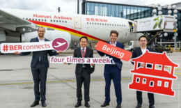 Bild zeigt 4 Männer vor einem Flugzeug der Hainan Airlines für die feierliche Bekanntmachung der Erweiterung der Flugverbindungen auf viermal pro Woche. Die Männer halten dazu Schilder vor sich, die das verdeutlichen.