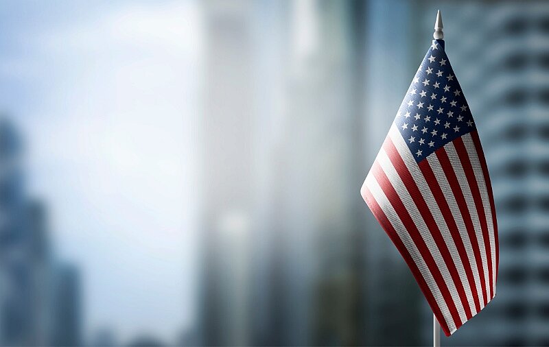 Flagge der USA im Vordergrund, Hintergrund unscharf Gebäude