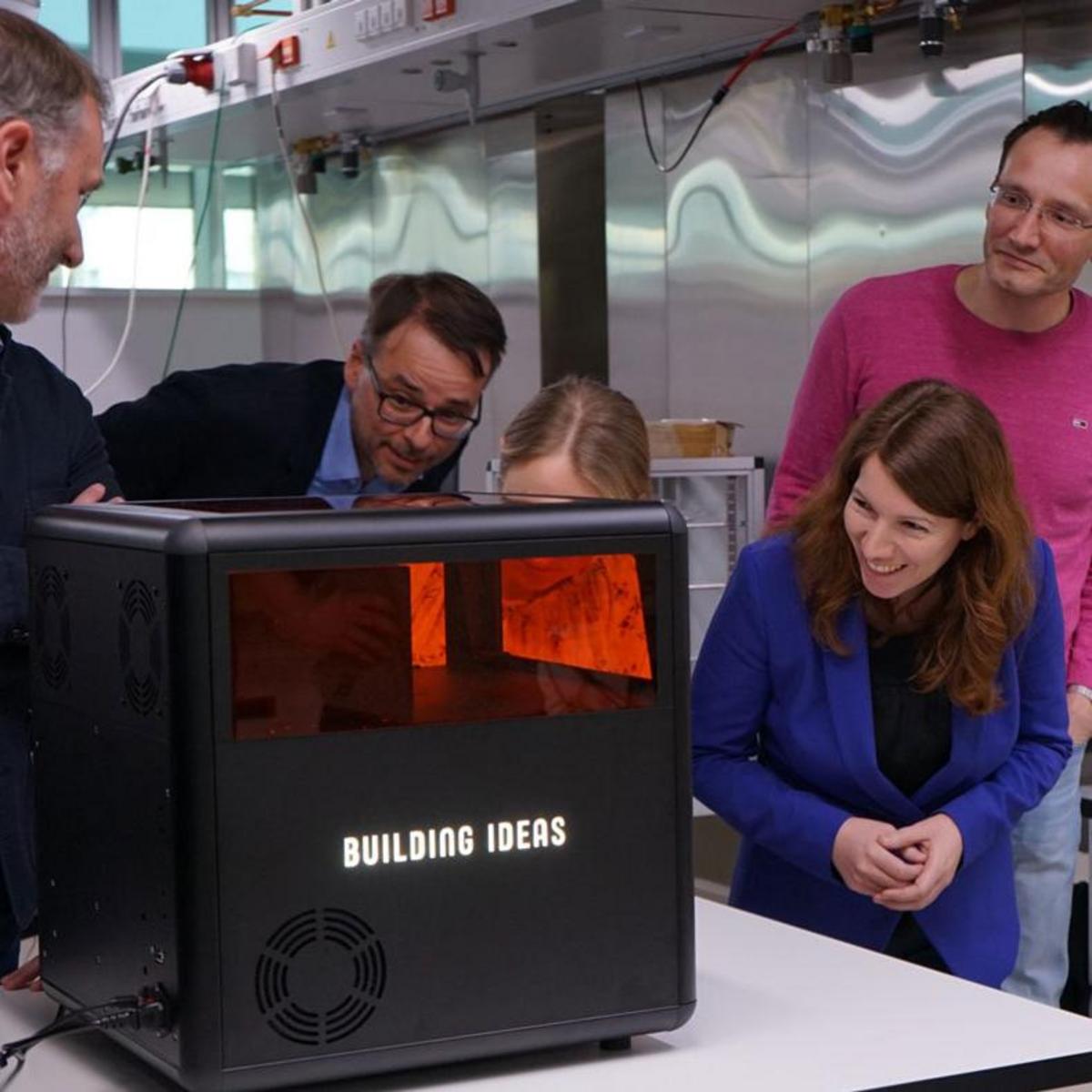 Menschen begutachten und bewundern den Xube, ein neuartiger 3D-Drucker der Xolo Gmbh aus Berlin Adlershof