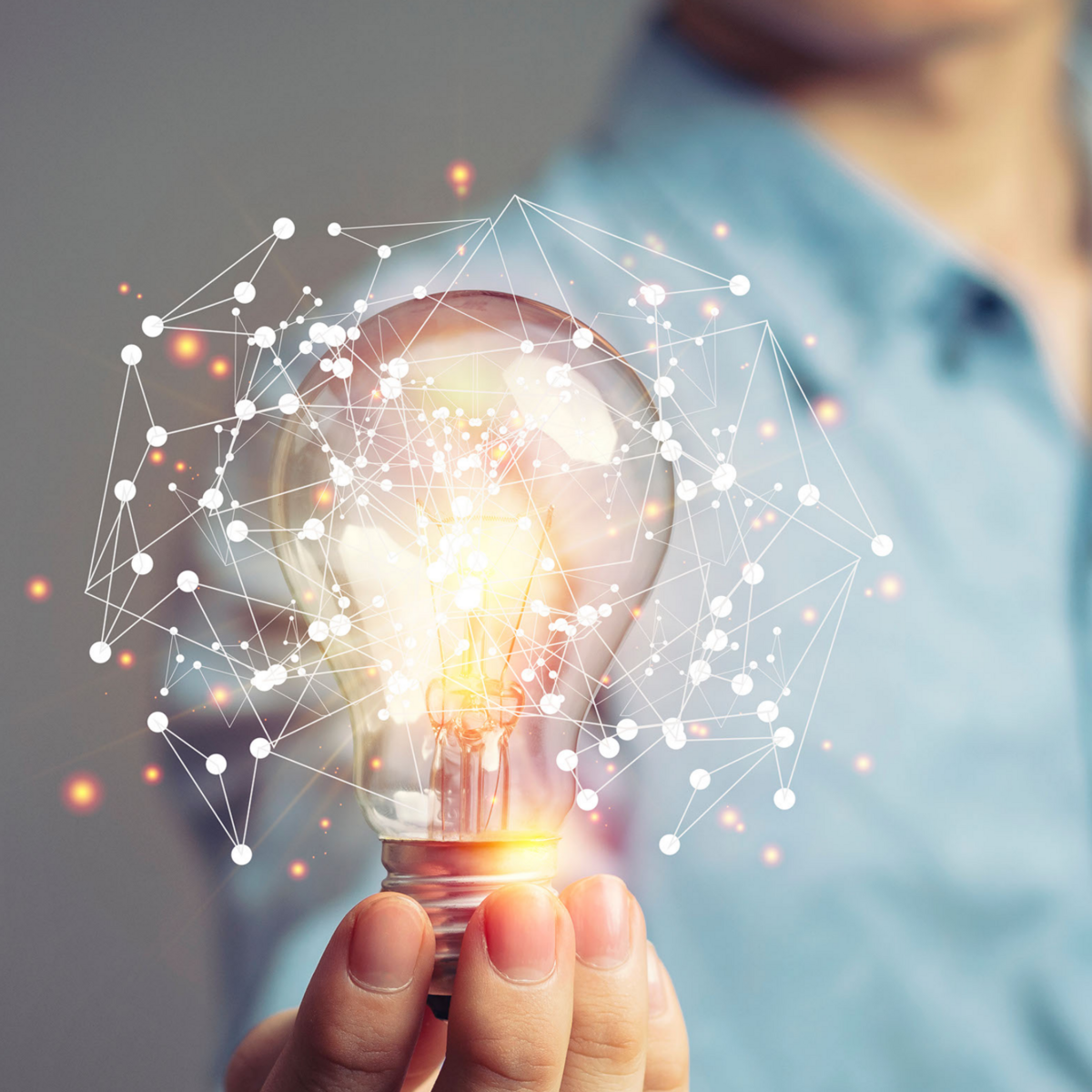 Mann hält Glühbirne, die ein schematisches Netzwerk umgibt - Sinnbild für Innovation
