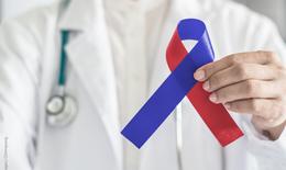 Arzt mit Stetoskop hält eine Charity-Schleife in rot und blau.