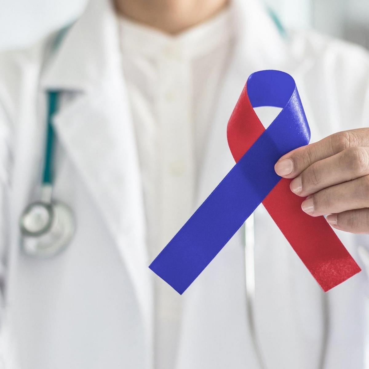 Arzt mit Stetoskop hält eine Charity-Schleife in rot und blau.