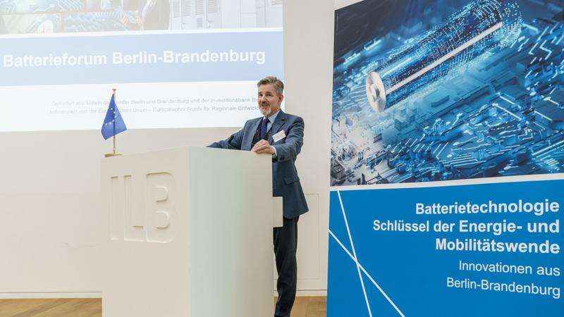 Dr. Kammradt, Sprecher der Geschäftsführung der Wirtschaftsförderung Land Brandenburg GmbH, hinter einem Podium zur Netzwerkveranstaltung "3. Batterieforum".
