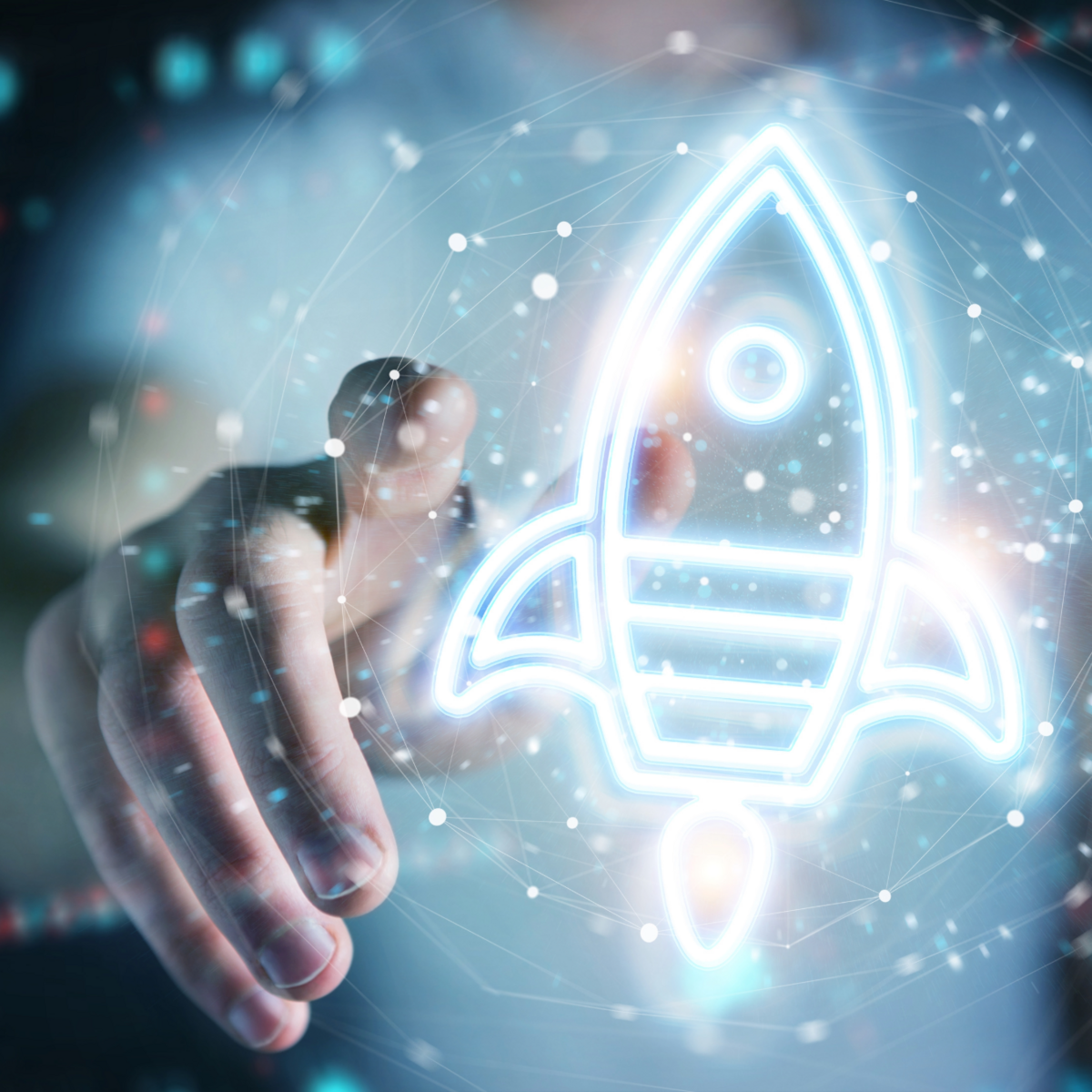 Bild zeigt eine Animation: im Hintergrund sieht man verschwommen den Oberkörper und den ausgestreckten Arm und die Hand einer Person. Die Hand klickt auf etwas. Im Vordergrund sieht man ein Piktogramm einer Rakete, die startet und eine Art Netzwerk drumherum. Diese Grafik symbolisiert ein neu gegründetes Unternehmen auf Erfolgskurs (Startup).