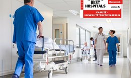 Krankenhausszene mit Krankenbett und Krankenpfleger und zwei krankenschwestern. Im Bild ist ein Siegel mit der Auszeichnung für die Charité.