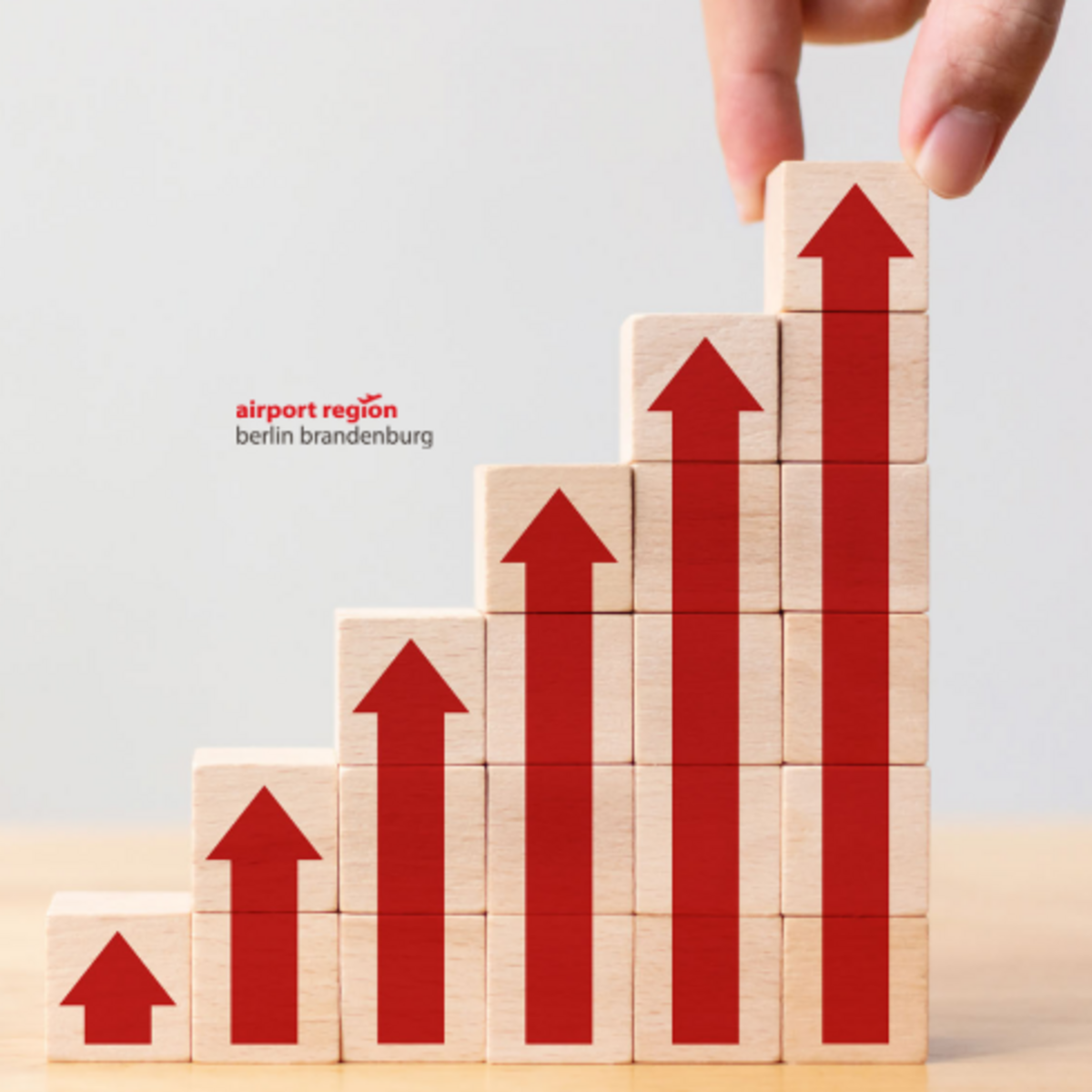 Rote Pfeile aufgemalt auf Holzstücken, führen treppenartig von links unten nach rechts oben und symbolisieren damit Wachstum und einen positive Entwicklung. 